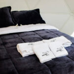 cama tendida con toallas limpias en un glamping